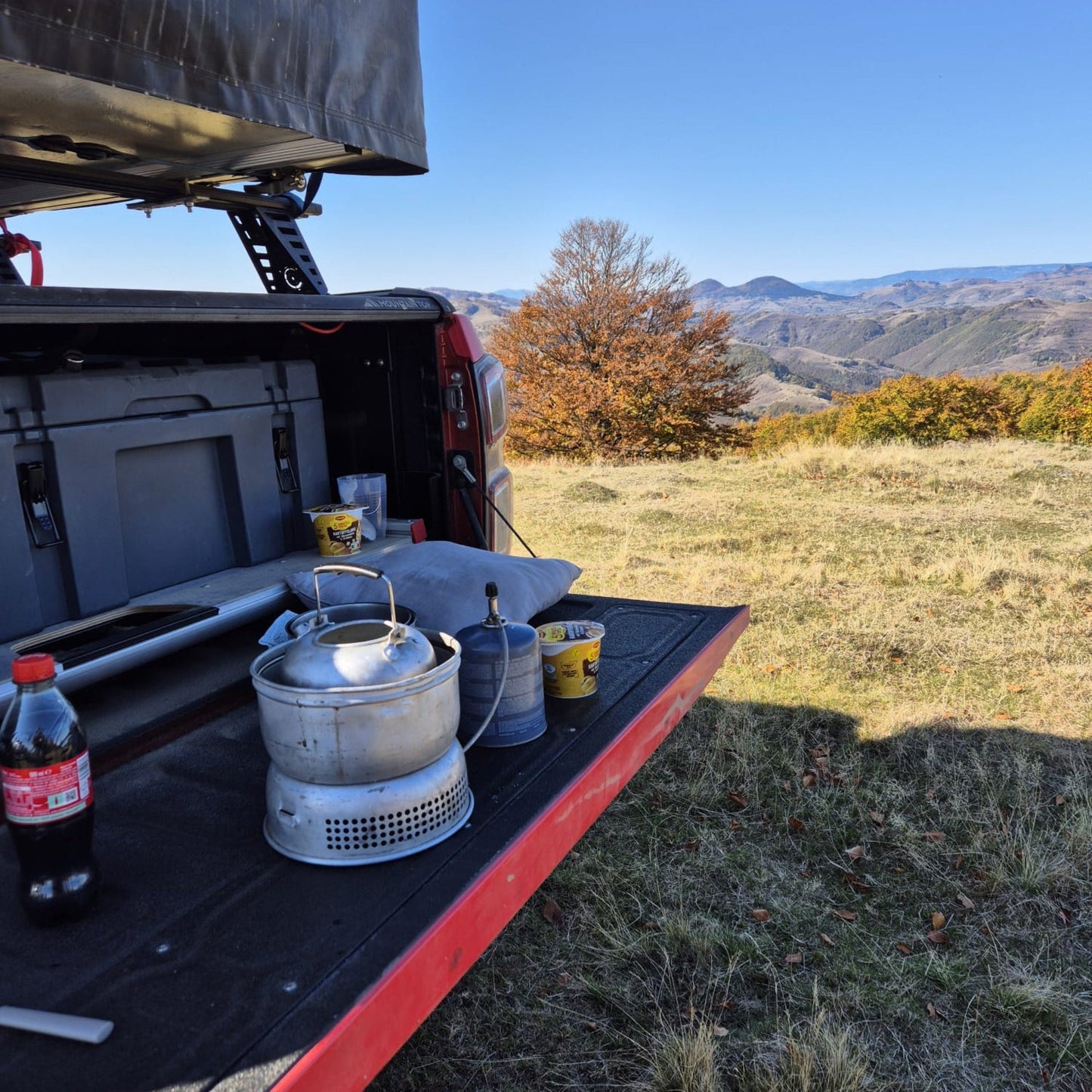 Outdoor-Kochsetup auf der Ladefläche eines Pick-ups mit Bergpanorama beim Dachzelt- und Allradcamp am DEKRA Lausitzring.