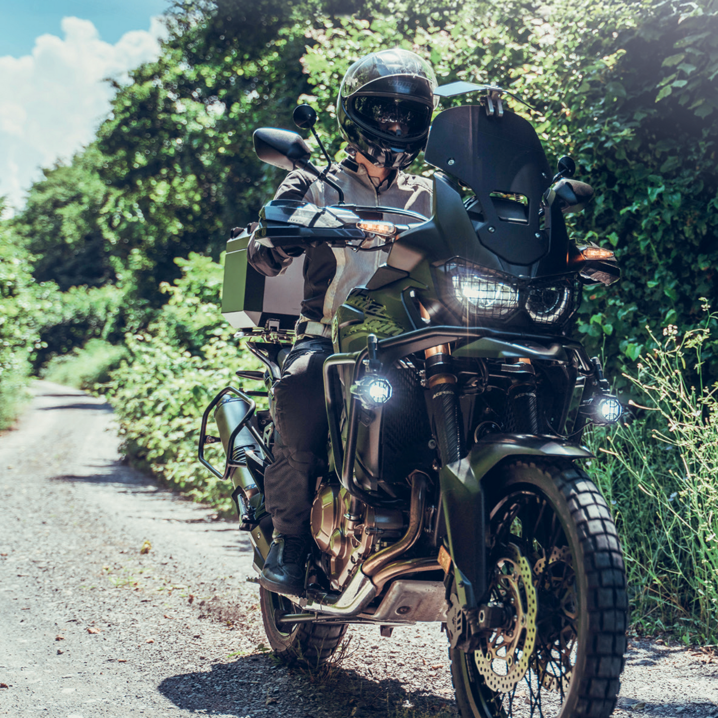 Teilnehmer des Reiseenduro Trainings am DEKRA Lausitzring fährt mit Reiseenduro über einen schmalen Offroad-Waldweg. Motorrad mit Schutzkleidung, Zusatzbeleuchtung und Geländeausrüstung.