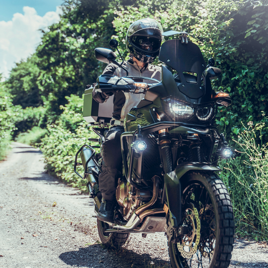 Teilnehmer des Reiseenduro Trainings am DEKRA Lausitzring fährt mit Reiseenduro über einen schmalen Offroad-Waldweg. Motorrad mit Schutzkleidung, Zusatzbeleuchtung und Geländeausrüstung.